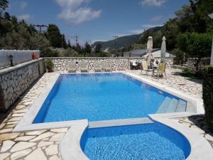 a swimming pool with chairs and an umbrella at AGIOS NIKITAS DOLPHINS in Agios Nikitas