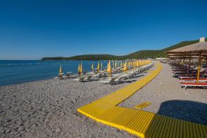 a beach with chairs and umbrellas and the water at Poseidon The Beach Hotel in Budva