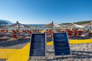 a beach with tables and chairs and umbrellas at Poseidon The Beach Hotel in Budva