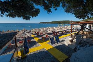 a beach with chairs and umbrellas and the ocean at Poseidon The Beach Hotel in Budva