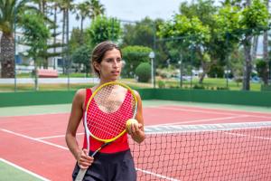 
a young woman holding a tennis racquet on a tennis court at Hotel Princesa Playa in Son Xoriguer
