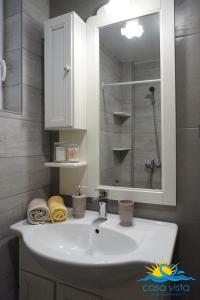 een badkamer met een witte wastafel en een spiegel bij Casa Vista Spring in Karpathos
