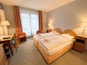 ein Hotelzimmer mit einem großen Bett und einem Schreibtisch in der Unterkunft REGIOHOTEL Wittekind Burg in Burg bei Magdeburg