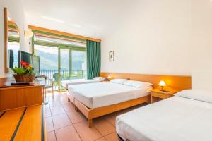 a hotel room with two beds and a balcony at Park Hotel Abbadia in Abbadia Lariana