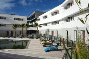 - un bâtiment avec des chaises et une piscine en face dans l'établissement Vacancéole - Le Terral - Montpellier Sud, à Saint-Jean-de-Védas