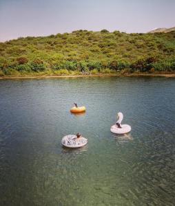 Drei Menschen sind auf aufblasbaren Booten in einem See. in der Unterkunft Lago da Garça Guesthouse in São Pedro do Sul