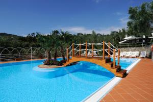 ein großes Schwimmbecken mit einer Holzbrücke darüber in der Unterkunft Camping Edy in Diano Marina