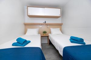 2 łóżka w pokoju z niebieskimi poduszkami w obiekcie Veda Mobile Home w Baskiej Vodzie