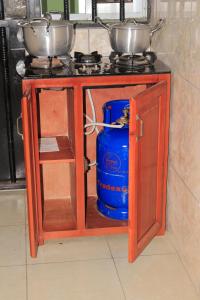 a stove with two pots and a blue bucket under it at Hotel Residence Madadjeu in Yaoundé