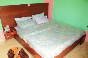 a bedroom with a large bed with a wooden headboard at Hotel Residence Madadjeu in Yaoundé