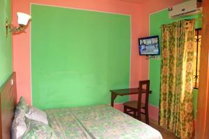 a bedroom with a green wall and a bed and a table at Hotel Residence Madadjeu in Yaoundé