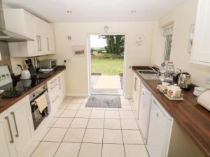 a kitchen with white cabinets and a tile floor at Garnedd in Holyhead