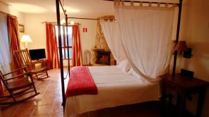 1 dormitorio con cama con dosel y TV en Casona De Navalmedio en Cercedilla