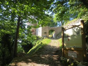 einen Weg zu den Ruinen einer Burg mit einem Schild in der Unterkunft La Maison des Fontaines d'Alsace in Ferrette