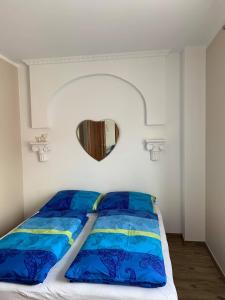 1 dormitorio con 1 cama con sábanas azules y espejo en Willa Solna, en Kołobrzeg