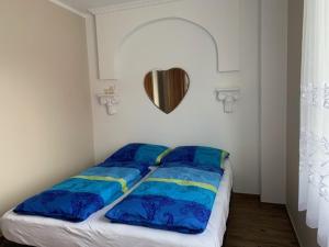 łóżko z niebieskimi i żółtymi poduszkami w pokoju w obiekcie Willa Solna w Kołobrzegu