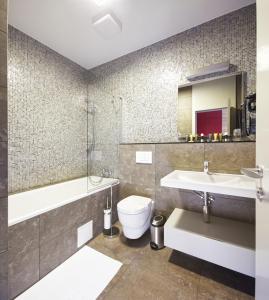 a bathroom with a sink and a toilet and a bath tub at Wellness Hotel ABÁCIE in Nový Jičín