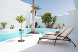 a patio with a chair and palm trees and a pool at Villa 44 in Corralejo