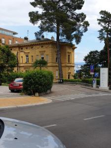 a yellow building with a tree in front of a street at Apartment Sea Promenade - Opatija center in Opatija