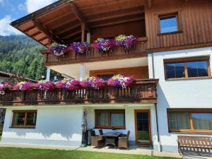 a house with a balcony with flowers on it at Ferienwohnung Auszeit Stubai in Fulpmes