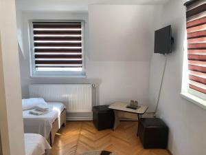 a room with two beds and a table and a window at Hotel Poenita in Sighişoara