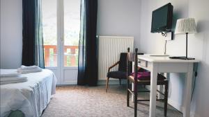 Dormitorio con escritorio, cama y TV en Le Brunet, en Saint-Jacques-des-Blats