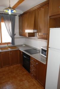 cocina con armarios de madera y nevera blanca en Apartamentos Rurales San Juan, en Castellnovo
