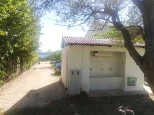 a small white building next to a dirt road at S&M camping in Sveti Filip i Jakov