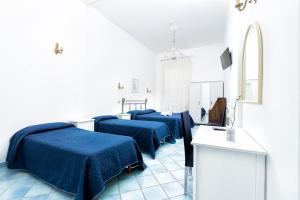 a room with four beds with blue sheets in it at Hotel Fontana in Amalfi