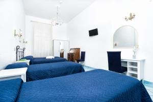 a bedroom with two beds and a desk and a mirror at Hotel Fontana in Amalfi