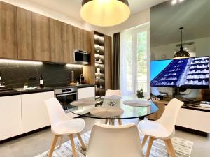 uma cozinha com uma mesa de vidro e cadeiras brancas em Maxim - Easy Home Booking em Nice