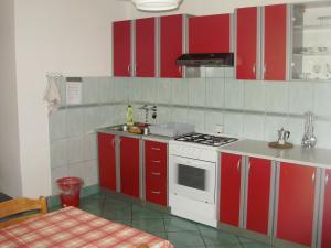 a kitchen with red cabinets and a white stove at Villa Welcome in Vrboska
