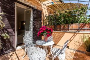d'une terrasse avec 2 chaises et une table fleurie. dans l'établissement Frattina Apartments, à Rome