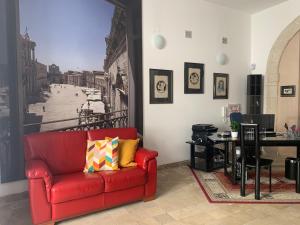 a living room with a red couch and a table at Nuova Mastrarua Rooms in Siracusa +24 photos