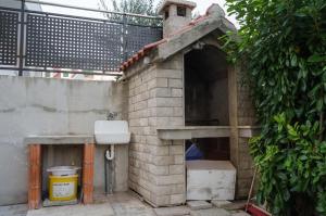 an outdoor brick oven with a sink and a trash can at APARTMANI MARIJA, Makarska - Promajna in Promajna