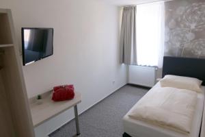 a bedroom with a bed and a tv on the wall at Hotel Waldoza in Waldmohr