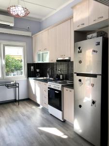 a kitchen with white cabinets and a white refrigerator at Industrial Design Bungalow – 2 min to Center, Wifi in Mytilene