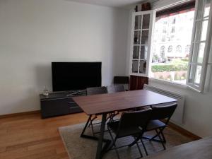 a living room with a table and chairs and a television at LE ROYAL (3 pièces au centre de DEAUVILLE) in Deauville