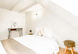 Un dormitorio blanco con una cama y una silla. en The downtown cosy apartments, en Colmar