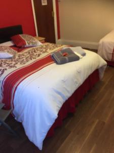 a large bed with a red and white blanket at Nights Inn in Slough