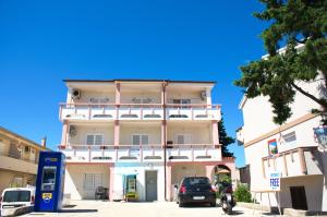 a tall building with a car parked in front of it at Apartmani Vidušin in Novalja