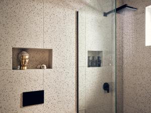 a shower with a statue of a head on a wall at Nomas Living in Kalamaki