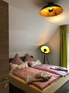 a bedroom with a bed with pink sheets and a light at Gästehaus Brunnenkunst - Exklusiv wohnen im Herzen der Stadt in Arnstadt