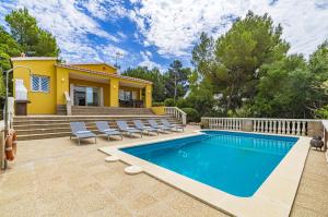 a pool in front of a house with chairs and a house at Villa Novas Park in Son Parc