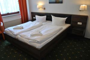 a bed with white sheets and two towels on it at Strand-Hotel Lobbe in Lobbe