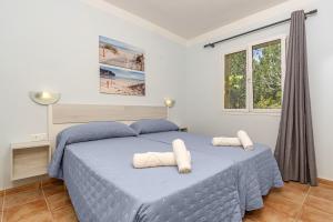 a bedroom with a blue bed with two towels on it at Villa Novas Park in Son Parc