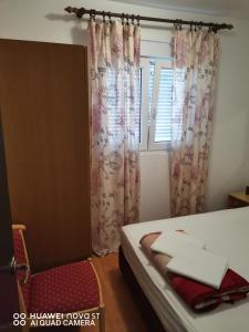 - une chambre avec un lit et une fenêtre avec des rideaux dans l'établissement Apartmani Bezek, à Ston