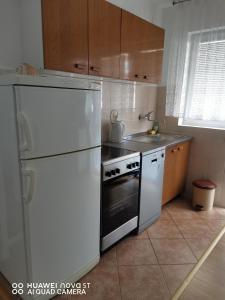 a kitchen with a white refrigerator and a stove at Apartmani Bezek in Ston