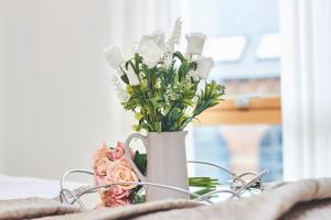 a white vase filled with flowers on a table at Deluxe Leeds City Centre Apt with Balcony View and Free Parking in Leeds