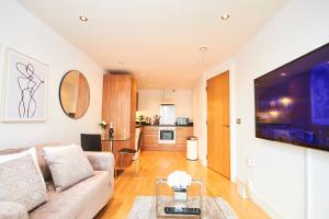 a living room with a couch and a tv at Deluxe Leeds City Centre Apt with Balcony View and Free Parking in Leeds